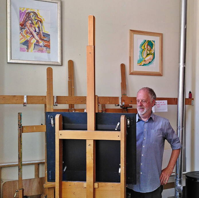 Hans Puts aan het werk in zijn atelier, op de achtergrond twee van zijn schilderijen Hans Puts aan het werk in zijn atelier, op de achtergrond twee van zijn schilderijen